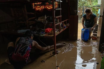 Người dân dọn bùn sau khi nhà của họ bị ngập do bão Yagi đổ bộ. (Ảnh: Reuters)