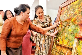 Nghệ nhân làng nghề sơn mài của Hà Nội giới thiệu sản phẩm tới Ðoàn công tác của Sở Công thương Viêng Chăn (Lào).