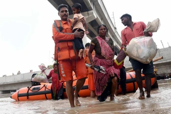 Người dân Ấn Ðộ sơ tán khỏi khu vực ngập lụt do mưa lớn. (Ảnh TÂN HOA XÃ)