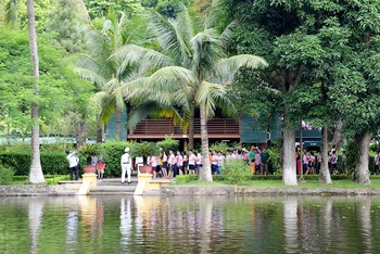 Học sinh tham quan nhà sàn, ao cá Bác Hồ trong Khu Di tích Chủ tịch Hồ Chí Minh tại Phủ Chủ tịch. (Ảnh Yến Kim)
