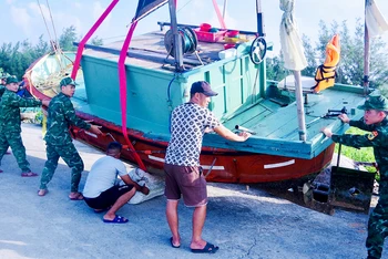 Lực lượng Biên phòng đảo Bạch Long Vĩ (Hải Phòng) hỗ trợ ngư dân di chuyển tàu thuyền lên bờ. (Ảnh SƠN HÀ)