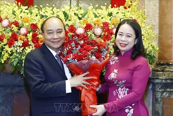 Quyền Chủ tịch nước Võ Thị Ánh Xuân tặng hoa nguyên Chủ tịch nước Nguyễn Xuân Phúc. (Ảnh: THỐNG NHẤT/TTXVN)