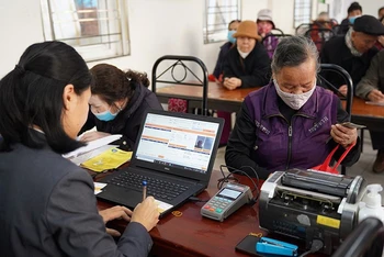 Chi trả lương hưu và trợ cấp bảo hiểm xã hội hằng tháng cho người dân tại phường Xuân Đỉnh, Hà Nội. (Ảnh: VNP)