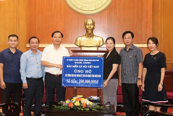 Phó Tổng Giám đốc Bảo hiểm xã hội Việt Nam Chu Mạnh Sinh trao 200 triệu đồng ủng hộ xây nhà đại đoàn kết cho hộ nghèo của tỉnh Điện Biên. (Ảnh: VSS)