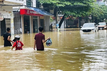 Người dân chạy lũ tại đường Thành Công, phường Nguyễn Thái Học, thành phố Yên Bái. (Ảnh: THANH SƠN)