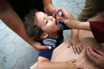 Một nhân viên y tế cho trẻ em Palestine uống vaccine bại liệt ở Deir Al-Balah, miền trung Gaza. (Ảnh UNRWA)