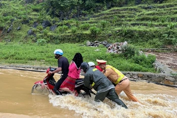 Cảnh sát giao thông Hà Giang lội nước đẩy xe máy, đưa người dân qua điểm ngập an toàn.
