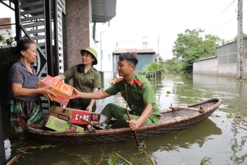 Cán bộ, chiến sĩ công an chèo thuyền mang thực phẩm đến tiếp tế cho người dân.