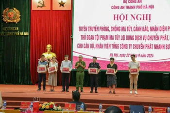 Phó Giám đốc Công an thành phố Hà Nội Nguyễn Thanh Tùng trao ấn phẩm tuyên truyền phòng chống ma túy cho đại diện các công ty chuyển phát nhanh bưu điện EMS.