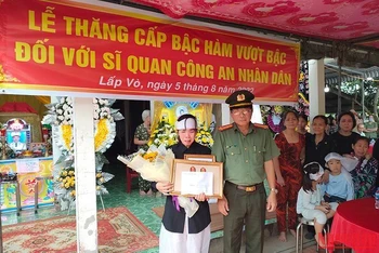 Đại tá Nguyễn Văn Hiểu - Giám đốc Công an tỉnh Đồng Tháp trao quyết định thăng cấp bậc hàm cho đồng chí Dương, vợ đồng chí Dương nhận. (Ảnh: HỮU NGHĨA)