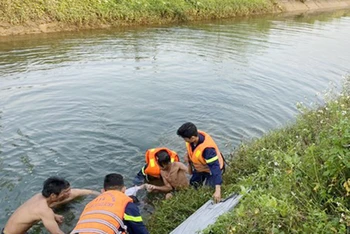 Lực lượng chức năng vớt thi thể anh P. dưới kênh thủy lợi Phú Ninh. 