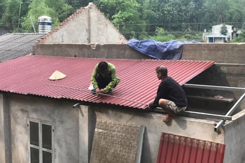 Người dân huyện Bạch Thông lợp lại mái nhà bị tốc do mưa lốc. (Ảnh: HƯƠNG DỊU)