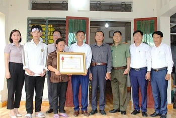 Đại diện đoàn công tác trao Huân chương Dũng cảm cho người thân anh Phạm Ngọc Anh.