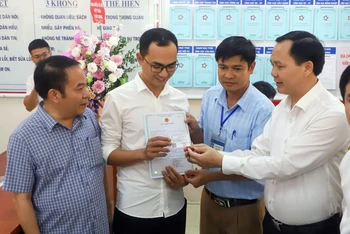 Đại diện Bảo hiểm Xã hội Việt Nam trao thẻ bảo hiểm y tế cho gia đình bé Đinh Bảo N. (huyện Thanh Liêm, tỉnh Hà Nam), là trẻ em đầu tiên được cấp giấy khai sinh, thẻ bảo hiểm y tế, đăng ký thường trú thông qua dịch vụ công liên thông.