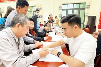 Cán bộ Trung tâm Phát triển quỹ đất huyện Thường Tín hướng dẫn người dân xã Văn Bình hoàn thiện thủ tục nhận tiền giải phóng mặt bằng dự án đường vành đai 4. (Ảnh: CÔNG TÂM)