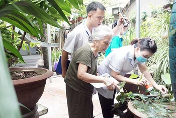 Cán bộ y tế hướng dẫn người dân trên địa bàn quận Long Biên kiểm tra và diệt bọ gậy. (Ảnh DUY TUÂN)