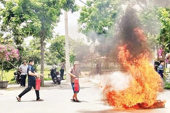 Người dân xã Yên Mỹ, huyện Thanh Trì thực hành sử dụng bình chữa cháy để dập lửa. (Ảnh NGUYỄN QUÂN)