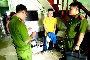 Cơ quan Cảnh sát điều tra Công an Bình Thuận đọc Quyết định khởi tố bị can, bắt tạm giam Nguyễn Quốc Đạt (đứng giữa, áo vàng). (Ảnh: Công an cung cấp)