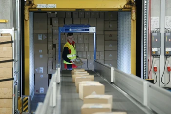 Một nhân viên đặt các bưu kiện lên băng chuyền tại trung tâm bưu kiện mới của DHL/Deutsche Post ở Bochum, Đức, ngày 18/11/2019. (Ảnh: REUTERS)