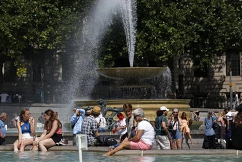 Người dân tránh nóng bên đài phun nước tại Quảng trường Trafalgar ở thủ đô London, Anh, ngày 17/6/2022. (Ảnh: AFP/TTXVN)