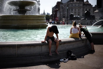 Người dân giải nhiệt cạnh đài phun nước Quảng trường Trafalgar trong đợt nắng nóng kỷ lục, London, Anh. (Ảnh: REUTERS)