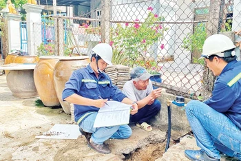 Nhân viên Xí nghiệp cấp nước Cần Giờ gắn đồng hồ nước thông minh thay cho đồng hồ cũ cho các hộ dân tại xã Tam Thôn Hiệp, huyện Cần Giờ.