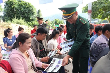 Cán bộ, chiến sĩ Bộ đội Biên phòng tỉnh Điện Biên phát tờ rơi tuyên truyền bảo vệ rừng đến nhân dân trên khu vực biên giới Việt-Lào.