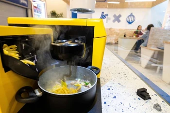Đầu bếp robot chế biến món ăn trong khi khách đang đợi món. Ảnh: Reuters.