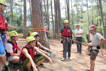 Kỹ thuật viên hướng dẫn du khách trước khi tham gia du lịch mạo hiểm đu dây vượt thác.