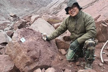 Nhà khảo cổ học Xing Lida bên cạnh dấu chân hóa thạch của khủng long. (Ảnh: globaltimes.com)