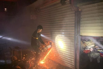 Lực lượng chức năng phải dùng cưa cưa cửa cuốn các ki-ốt trong chợ thị xã Buôn Hồ chữa cháy.