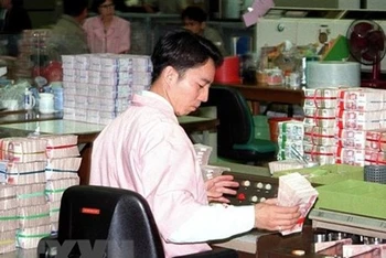 Nhân viên kiểm tra những cọc tiền baht Thai tại ngân hàng Trung ương ở Bangkok, Thái Lan. (Ảnh: AFP/TTXVN)