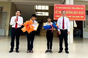 Giám đốc Sở Nội vụ tỉnh Đồng Nai Trần Quang Tú và Trưởng ban Thi đua Khen thưởng tỉnh Đồng Nai Thái Bình Dương trao tặng Bằng khen và hoa cho 2 em Lê Bảo Trâm và Nguyễn Quốc Kỳ.