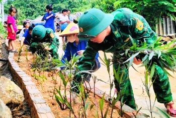 Thanh niên cùng lực lượng vũ trang trồng hoa bên đường nội bản Con Dao, xã Quang Chiểu.