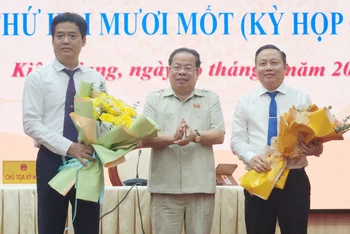 Chủ tịch Hội đồng nhân dân tỉnh Kiên Giang Mai Văn Huỳnh tặng hoa chúc mừng ông Lê Quốc Anh (bìa trái) và ông Lê Hữu Toàn (bìa phải).