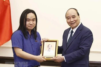 Chủ tịch nước Nguyễn Xuân Phúc tặng ảnh Chủ tịch Hồ Chí Minh cho dịch giả trẻ Nguyễn Bình. (Ảnh: Thống Nhất/TTXVN) 