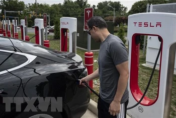Người dân sạc điện cho ô-tô tại một trạm sạc của Tesla ở Arlington, Virginia, Mỹ. (Ảnh: AFP/TTXVN)