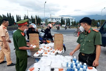 Cán bộ, chiến sĩ chuẩn bị phần ăn và nhiệt tình tiếp sức cho người đi xe gắn máy từ các tỉnh phía nam về các tỉnh miền trung vui Tết khi ngang qua điểm hỗ trợ tại huyện Thuận Bắc, tỉnh Ninh Thuận. 