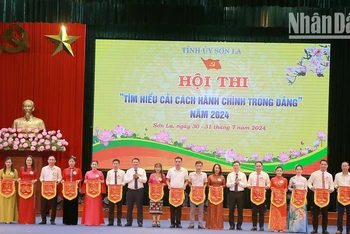 Đồng chí Phó Bí thư Thường trực Tỉnh ủy Sơn La và Ban tổ chức Hội thi trao cờ lưu niệm cho các đội thi.