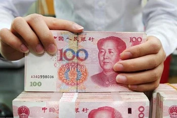 Nhân viên ngân hàng kiểm tiền mệnh giá 100 nhân dân tệ tại tỉnh Giang Tô, Trung Quốc. (Ảnh: AFP/TTXVN)