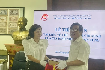 Giám đốc Trung tâm Lưu trữ Quốc gia III Trần Việt Hoa (bên trái) tiếp nhận các tài liệu của nhà văn Sơn Tùng từ ông Bùi Sơn Định - con trai cố nhà văn.