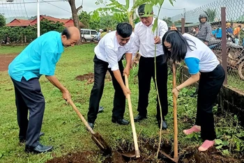 Các đại biểu tham gia trồng cây trong khuôn viên nhà rông làng Kép 1.