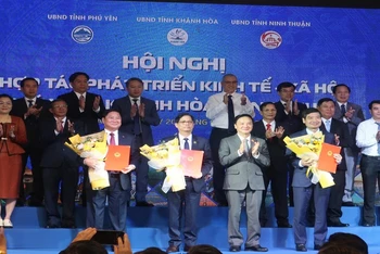 Phó Chủ tịch Quốc hội Nguyễn Khắc Định (hàng trước, thứ hai từ phải sang) tặng hoa lãnh đạo các tỉnh Khánh Hòa, Phú Yên và Ninh Thuận tại lễ ký kết. (Ảnh: PHONG NGUYÊN) 