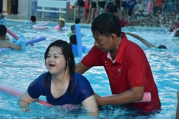 Các em khuyết tật được các thầy hướng dẫn dạy tập làm quen với nước.