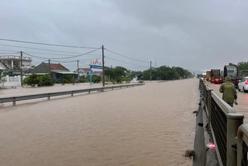 Nước ngập trên tuyến quốc lộ 1 đoạn qua xã an Mỹ, huyện Tuy An (Km1315), lực lượng chức năng điều tiết giao thông bảo đảm an toàn các phương tiện.