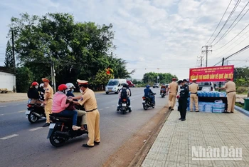 Lực lượng Cảnh sát giao thông Công an tỉnh Đồng Nai phát nước suối, khăn lạnh cho người dân về quê đón Tết trên quốc lộ 20.