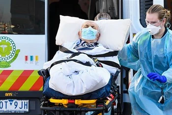 Nhân viên y tế chuyển bệnh nhân Covid-19 tại Melbourne, Australia. (Ảnh: AFP/TTXVN)