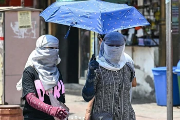 Người dân di chuyển dưới trời nắng nóng tại New Delhi, Ấn Độ. (Ảnh: AFP/TTXVN)