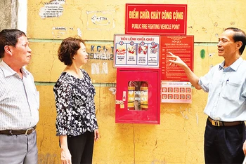 Ông Trương Ðình Quý (bên phải), Bí thư Chi bộ kiêm Trưởng ban Công tác Mặt trận Tổ dân phố số 5, phường Trung Văn hướng dẫn người dân sử dụng phương tiện chữa cháy. 
