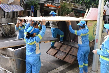 Công nhân Công ty TNHH một thành viên Môi trường đô thị Hà Nội dọn vệ sinh trên tuyến phố Triệu Việt Vương. (Ảnh lam vy) 